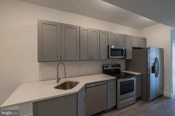 a kitchen with stainless steel appliances granite countertop a sink a microwave a refrigerator and cabinets