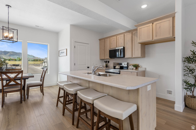 636 West Caroles Way, Unit 7 Tooele, UT 84074 - Photo 12 of 31 Open concept kitchen and dining area featuring light wood-finish cabinetry, stainless steel appliances, and a kitchen island with seating
