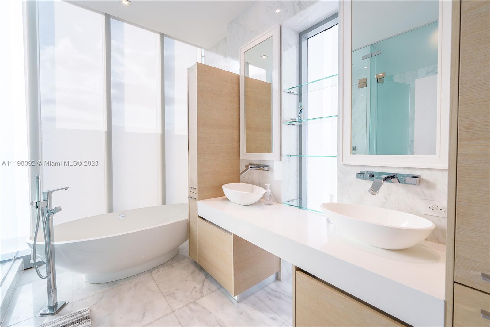 9501 Collins Avenue, Unit 1 Surfside, FL 33154 - Photo 12 of 35 a bathroom with a granite countertop tub sink and mirror
