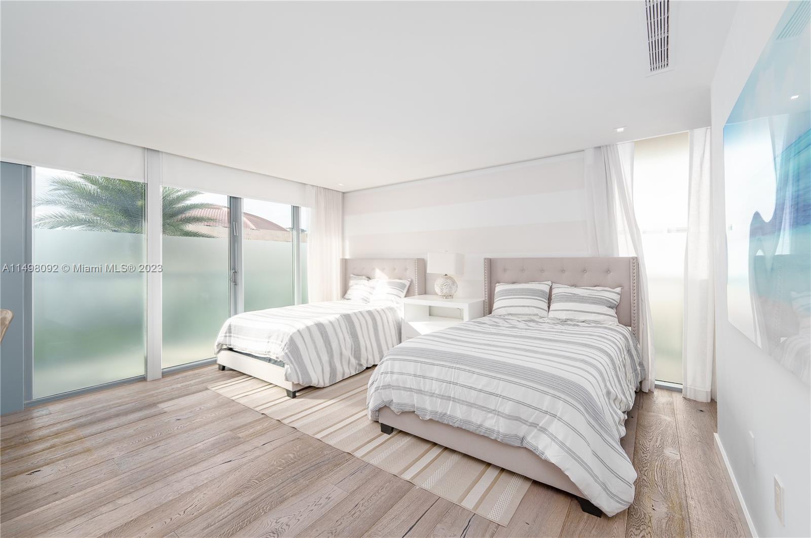 9501 Collins Avenue, Unit 1 Surfside, FL 33154 - Photo 19 of 35 a bedroom with two beds and wooden floor