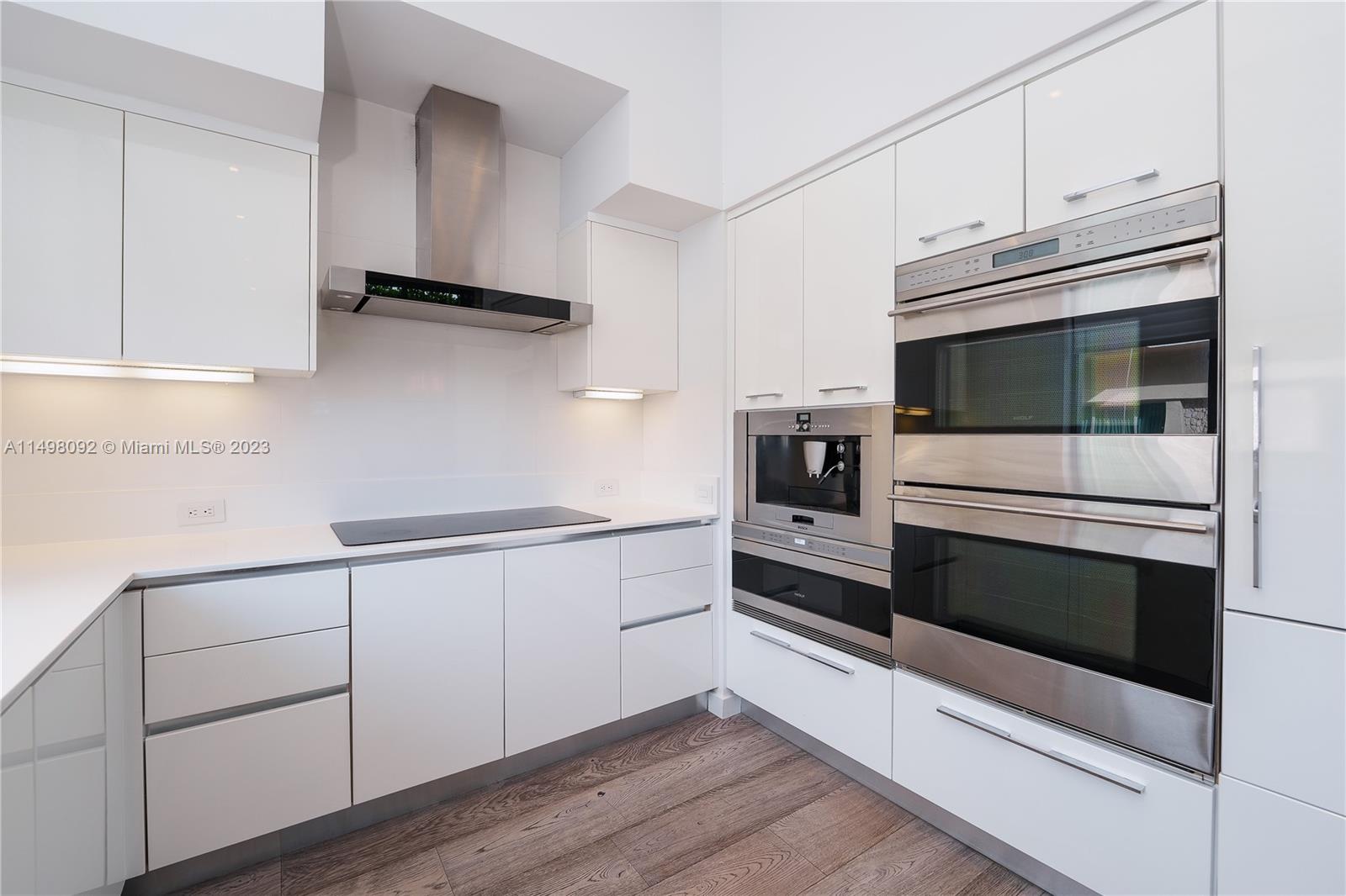 9501 Collins Avenue, Unit 1 Surfside, FL 33154 - Photo 8 of 35 a kitchen with white cabinets and stainless steel appliances