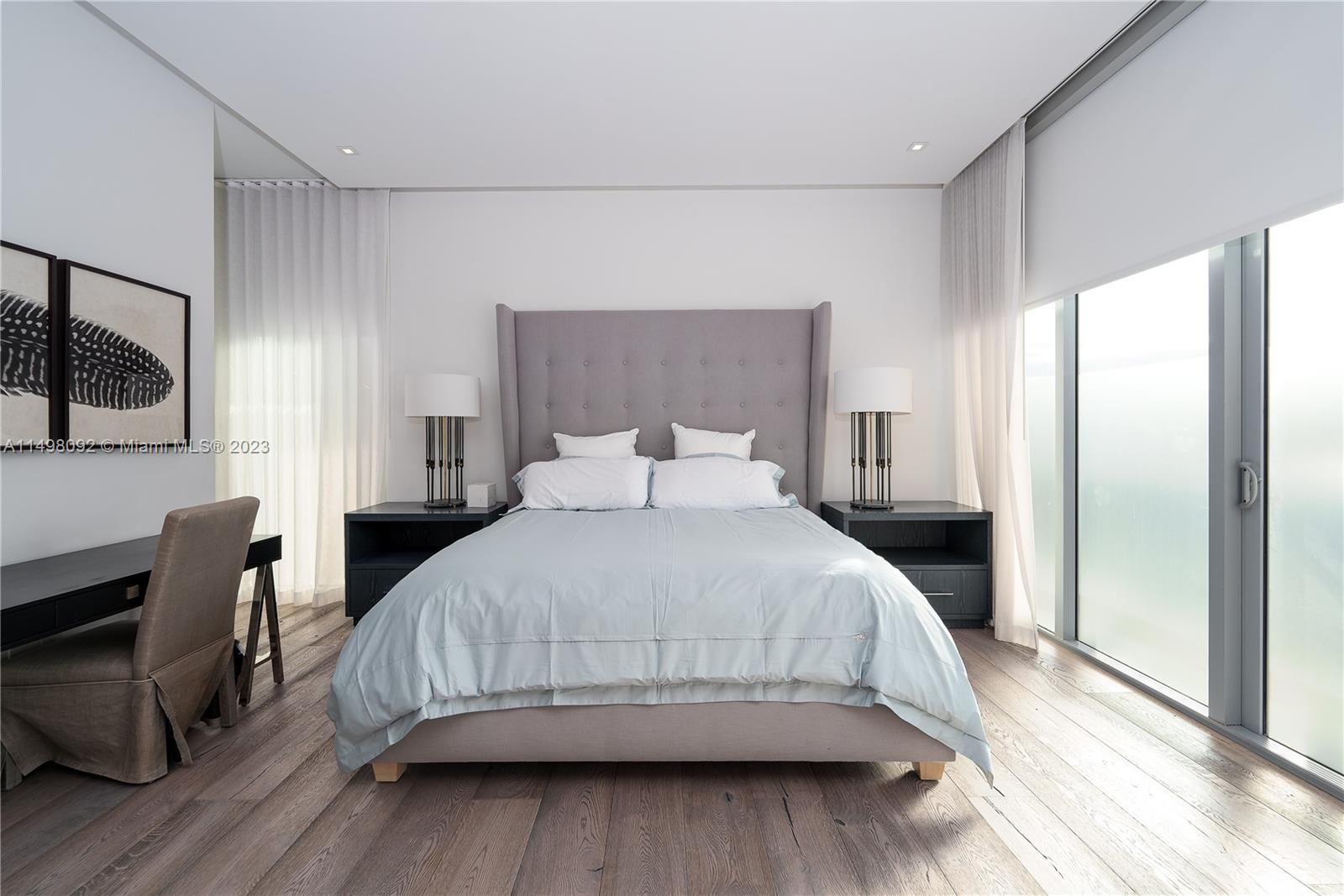 9501 Collins Avenue, Unit 1 Surfside, FL 33154 - Photo 10 of 35 a bedroom with a bed a mirror on dresser and a wooden floor