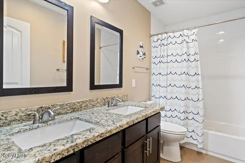 a bathroom with a granite countertop sink a toilet and a mirror