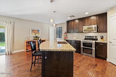 a kitchen with stainless steel appliances granite countertop a stove top oven a sink a dining table and chairs