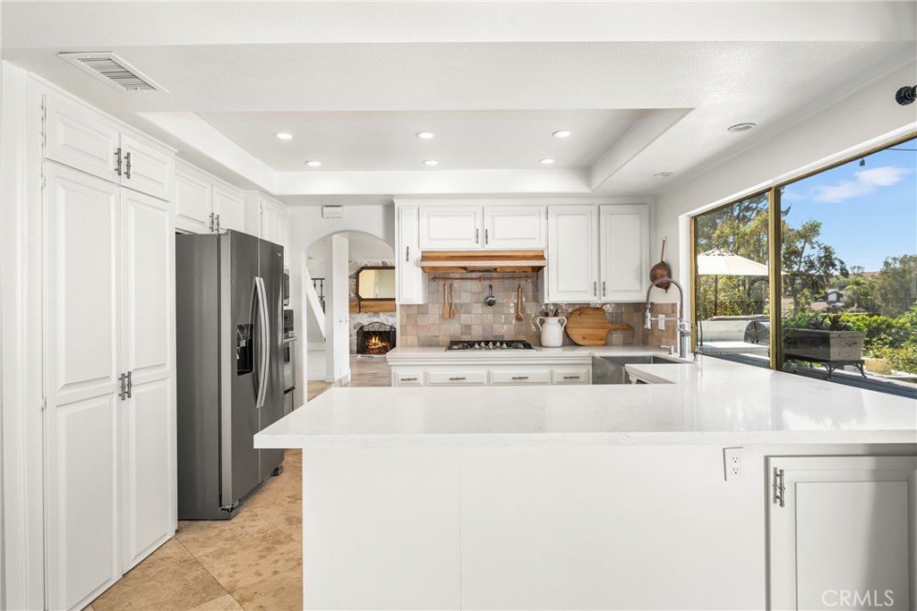 a large kitchen with stainless steel appliances kitchen island a large counter top and a refrigerator
