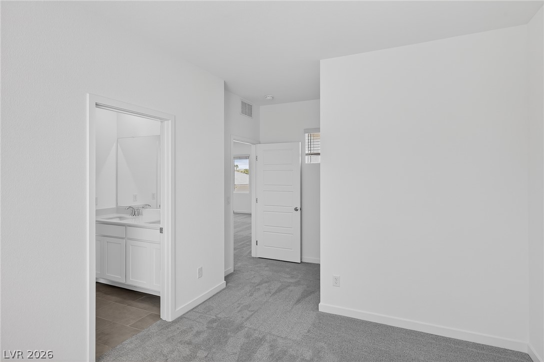 347 Sam Way Mesquite, NV 89027 - Photo 15 of 32 A well-lit bedroom with plush carpeting offers convenient access to a modern bathroom with a double vanity.