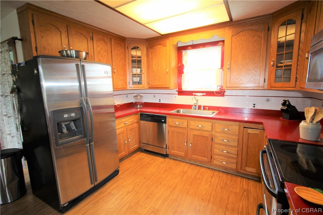 1502 Gdn Crk Road Mathews, VA 23109 - Photo 12 of 50 Kitchen featuring light hardwood flooring, stainless steel appliances, backsplash, and brown cabinets