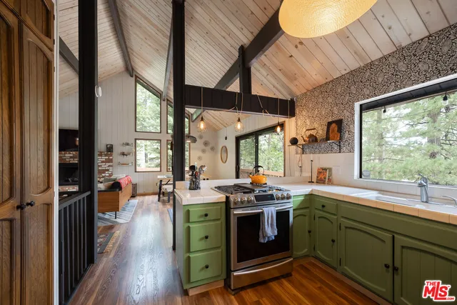 a kitchen with stainless steel appliances a refrigerator a sink a stove and white cabinets with wooden floor