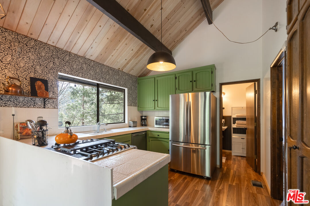 26645 Lake Forest Drive Twin Peaks, CA 92391 - Photo 7 of 30 a kitchen with stainless steel appliances a refrigerator a sink a stove and white cabinets with wooden floor