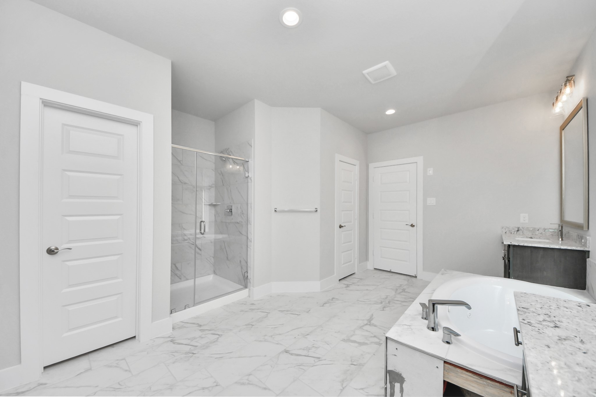 3023 Native Spg Drive Spring, TX 77373 - Photo 28 of 50 Escape to a spa-like oasis in this primary bathroom. Enjoy a walk-in shower with tile surround, a separate garden tub with custom detailing, and an elegant vanity featuring light countertops, modern hardware, and beautiful vanity lights. Experience luxury and relaxation in every detail.