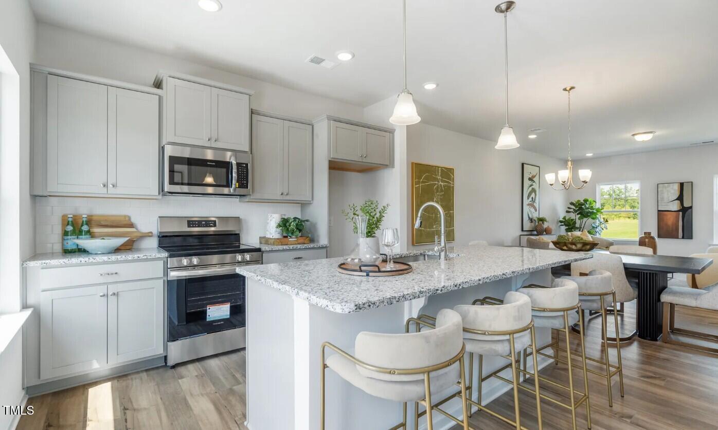 732 Orch Vista Circle Raleigh, NC 27606 - Photo 10 of 19 a kitchen with stainless steel appliances granite countertop a stove a sink a microwave a dining table and chairs