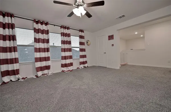 a view of a livingroom with a chandelier fan and windows