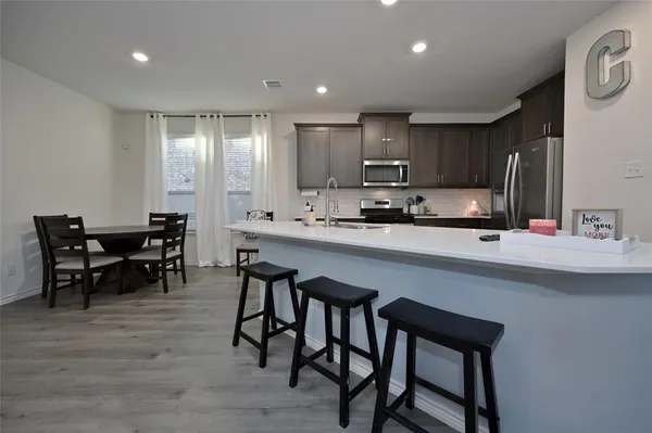 a kitchen with kitchen island granite countertop a dining table chairs cabinets and stainless steel appliances