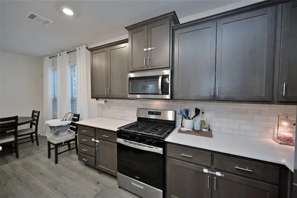 a kitchen with granite countertop a stove a sink and a microwave