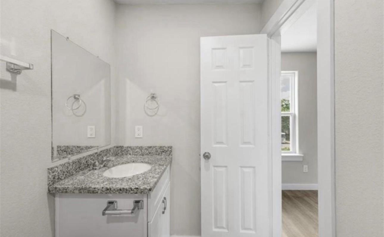 6801 Haight Street, Unit B Houston, TX 77028 - Photo 4 of 8 a bathroom with a granite countertop sink and a mirror