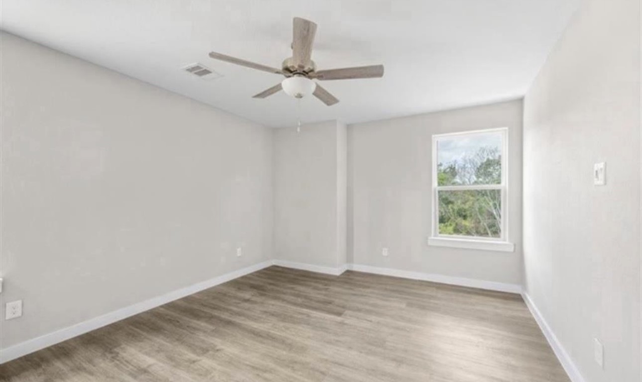 6801 Haight Street, Unit B Houston, TX 77028 - Photo 6 of 8 an empty room with wooden floor fan and windows