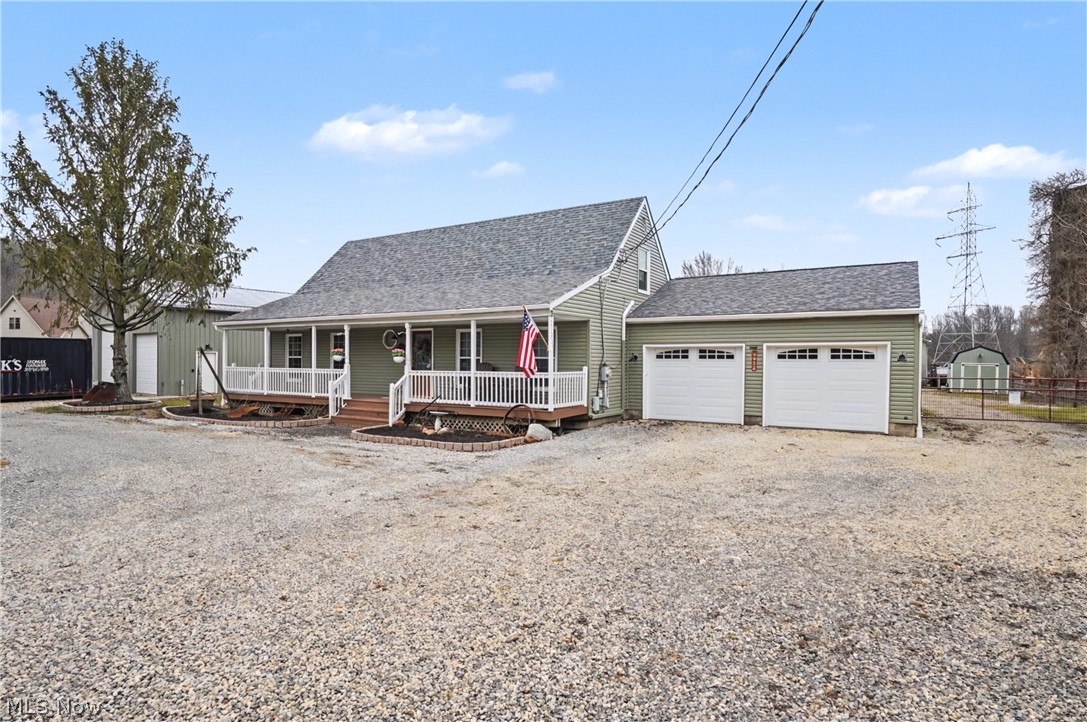 View of front of house with a shingled roof, a porch, gravel driveway, and an attached garage