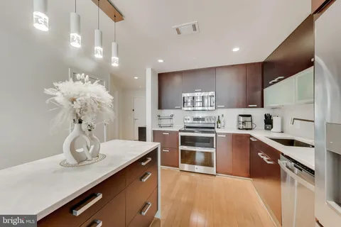 a kitchen with stainless steel appliances kitchen island granite countertop a sink dishwasher a stove a refrigerator and island with wooden floor