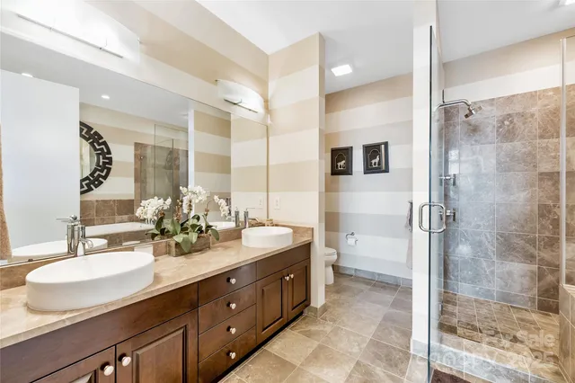 a bathroom with a double vanity sink toilet mirror and shower