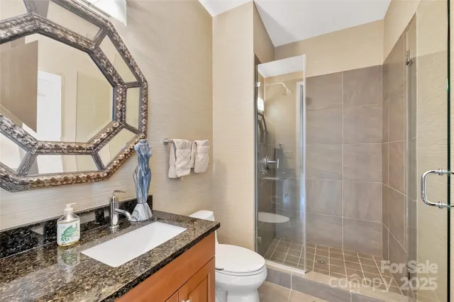 a bathroom with a granite countertop sink a mirror and a shower