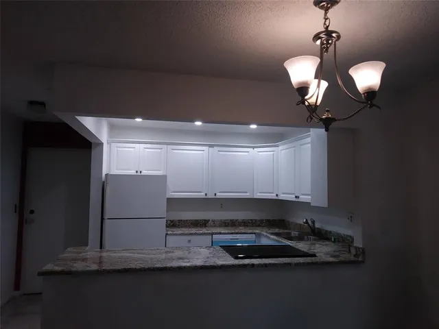 a kitchen with kitchen island granite countertop cabinets and refrigerator