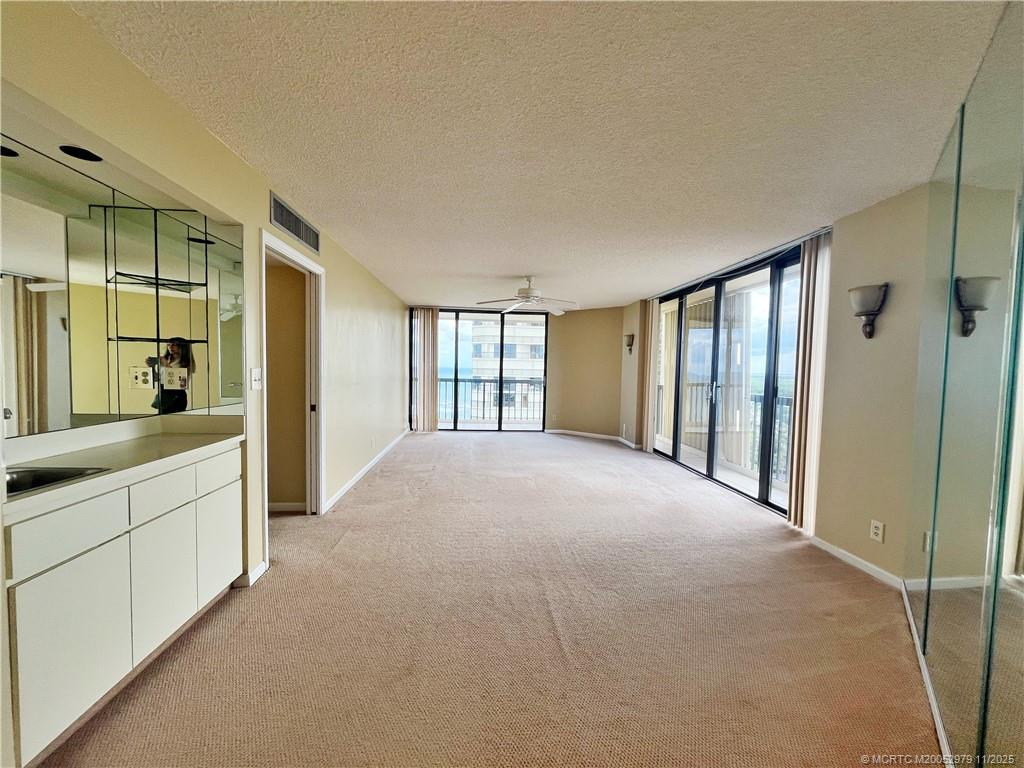 9500 South Ocean Drive, Unit 1410 Jensen Beach, FL 34957 - Photo 3 of 17 a large white room with windows and chandelier