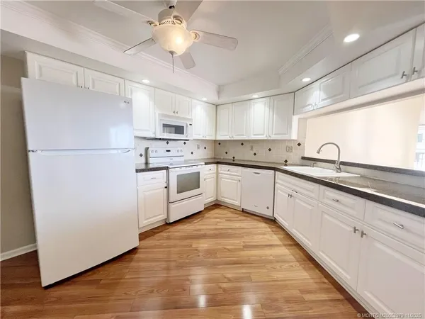a large white kitchen with cabinets a sink and a stove