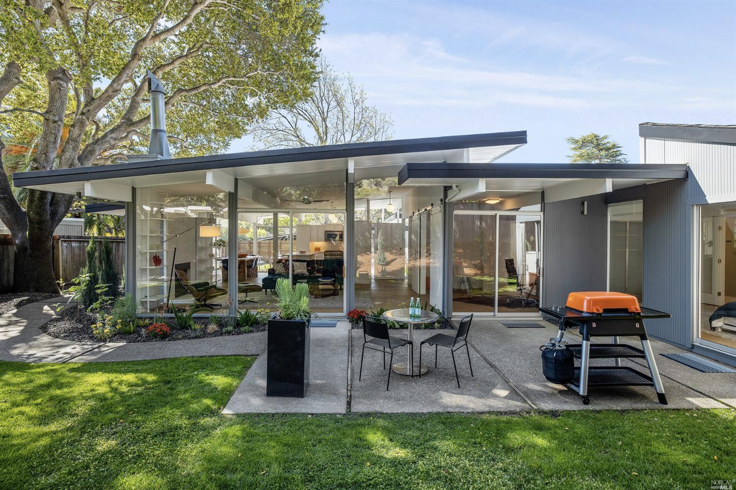 a view of a patio with table and chairs potted plants and floor to ceiling window