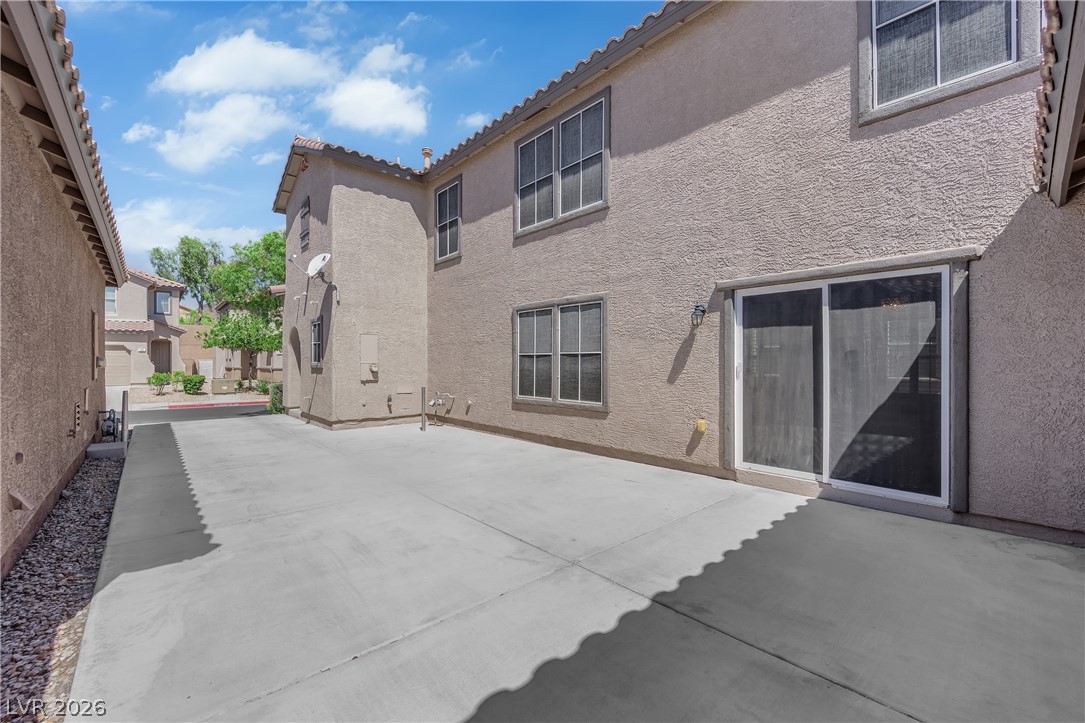 646 Monument Point Street Henderson, NV 89002 - Photo 3 of 44 Concrete patio leads to sliding glass doors on this stucco-finished townhouse.
