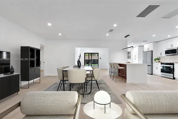 a living room with furniture kitchen view and a wooden floor