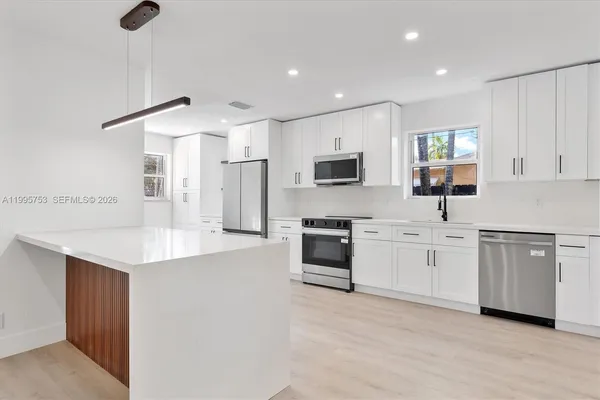 a kitchen with white cabinets and appliances
