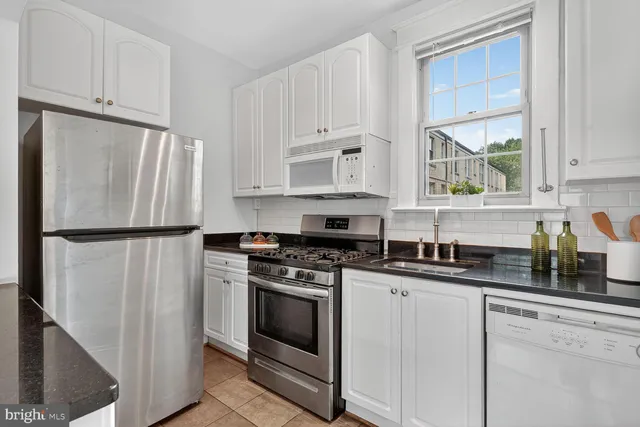 a kitchen with granite countertop white cabinets white stainless steel appliances and a refrigerator