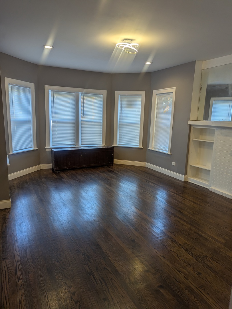 7936 South Champlain Avenue, Unit 1 Chicago, IL 60619 - Photo 2 of 8 an empty room with wooden floor and windows
