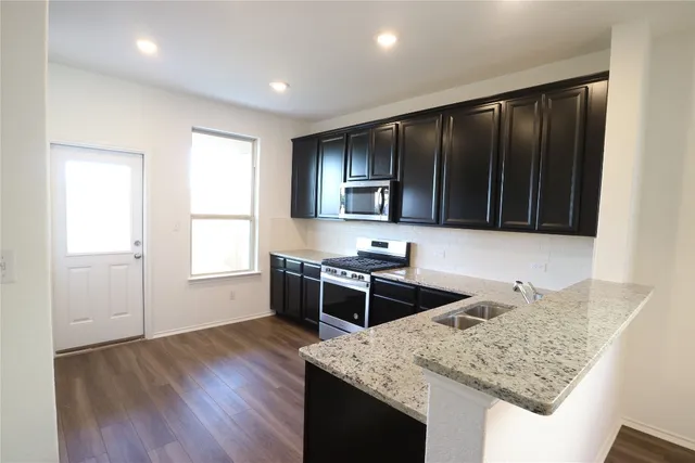 a kitchen with stainless steel appliances granite countertop hardwood floor sink stove and granite counter top