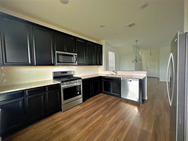 a kitchen with stainless steel appliances kitchen island granite countertop a stove a sink and a refrigerator