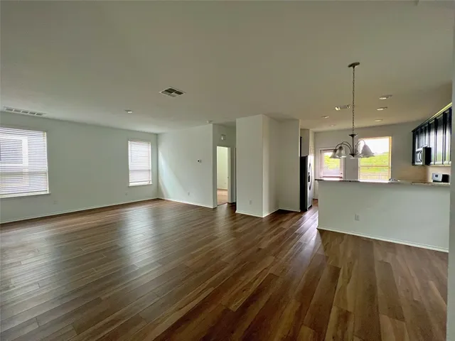a view of an empty room with window and wooden floor
