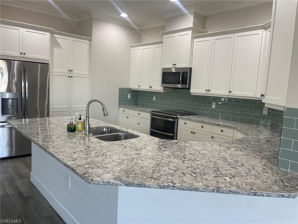 5685 Highbourne Drive Naples, FL 34113 - Photo 18 of 26 a kitchen with granite countertop a sink a stove and cabinets
