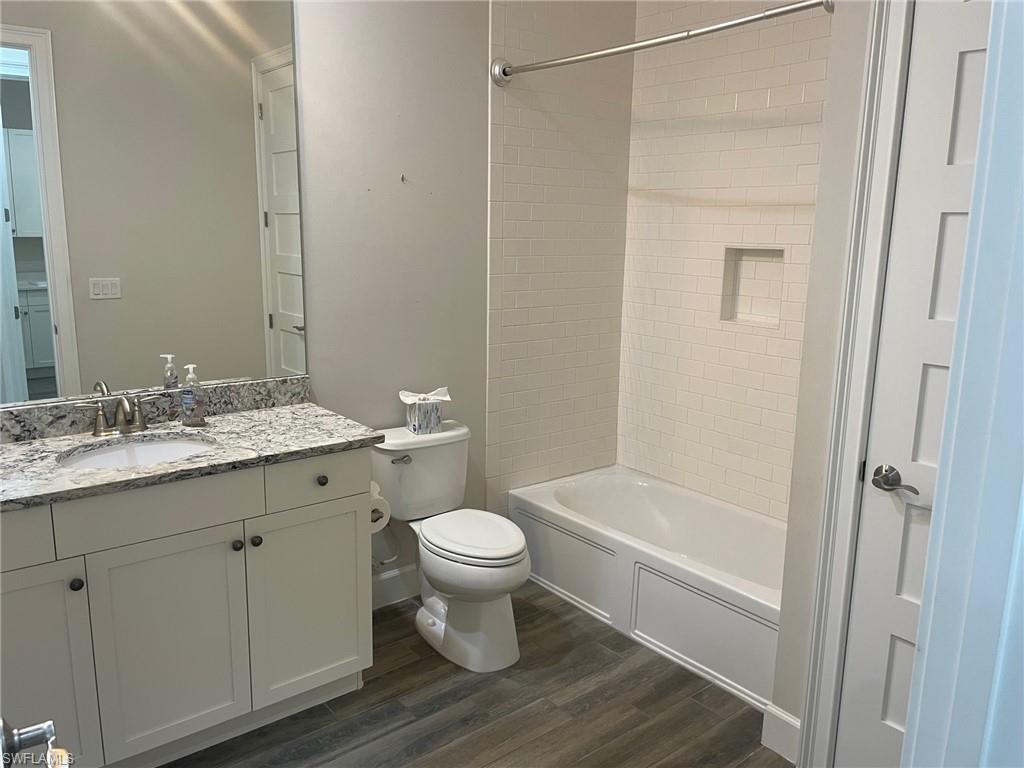 5685 Highbourne Drive Naples, FL 34113 - Photo 7 of 26 a bathroom with a granite countertop sink toilet a shower and a mirror