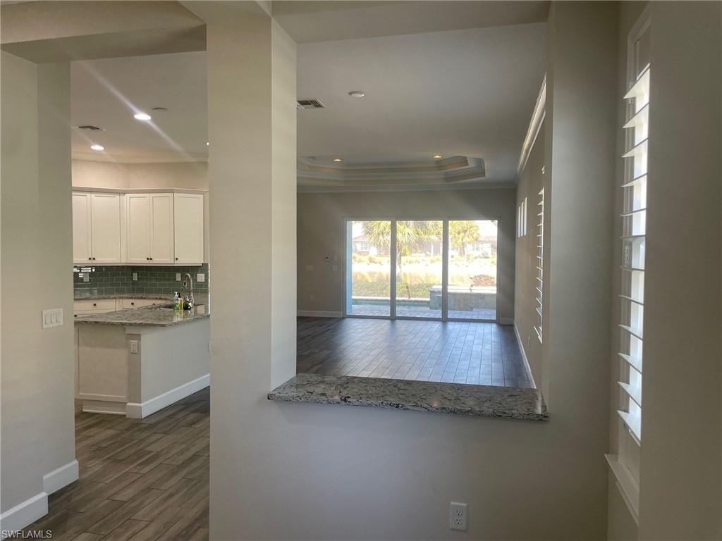 5685 Highbourne Drive Naples, FL 34113 - Photo 8 of 26 a view of a hallway with wooden floor and a kitchen