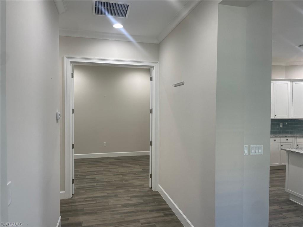 5685 Highbourne Drive Naples, FL 34113 - Photo 9 of 26 a view of a hallway with wooden floor and a bathroom