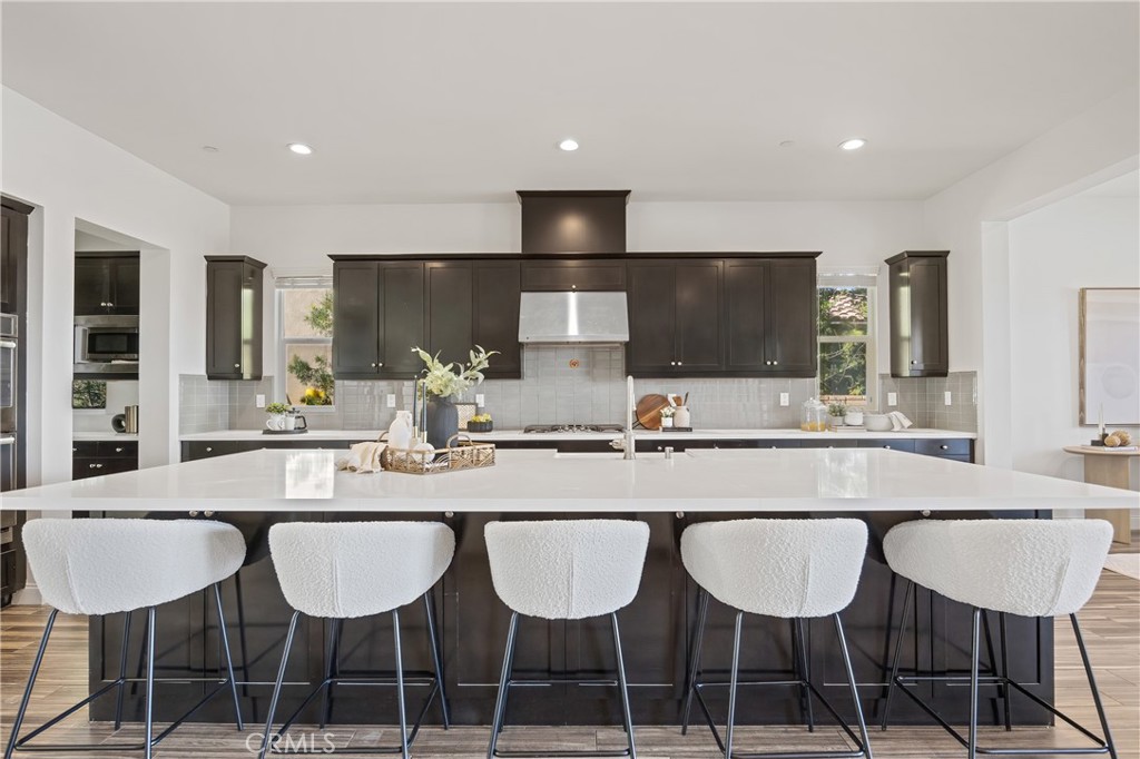 24910 Old Stone Way Stevenson Ranch, CA 91381 - Photo 22 of 67 a kitchen with granite countertop a dining table chairs cabinets and stainless steel appliances