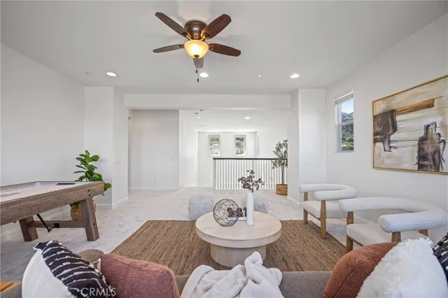 a view of a white house with a large pool and a yard with plants and a large tree