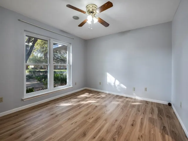 a view of an empty room with window and wooden floor