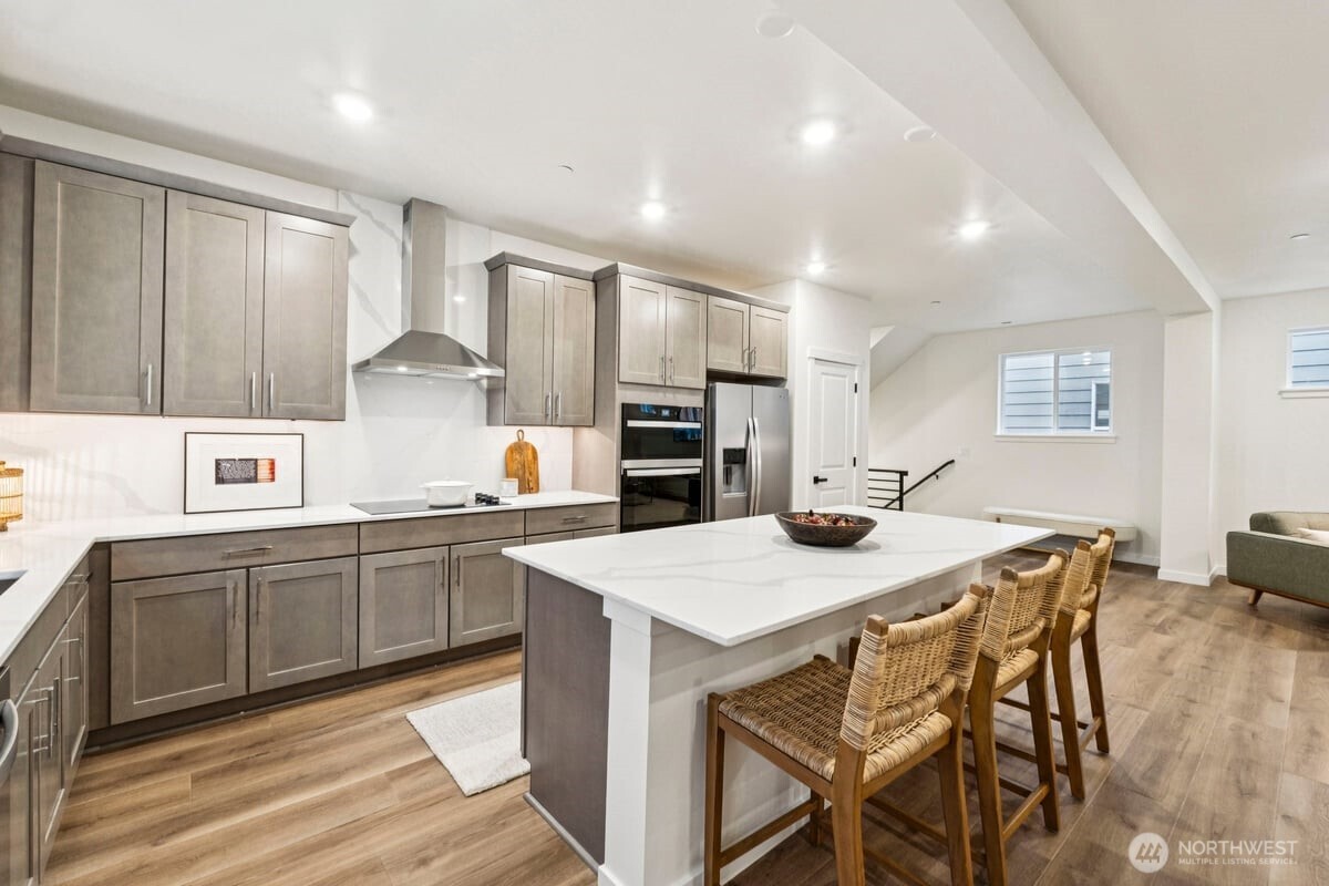 24233 13 Avenue Southeast, Unit CR26 Bothell, WA 98021 - Photo 7 of 21 a kitchen with stainless steel appliances kitchen island granite countertop a table chairs sink and cabinets