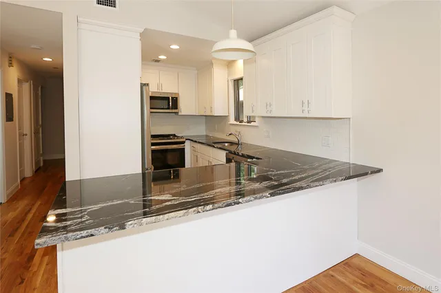 a view of a kitchen with wooden floor and stainless steel appliances