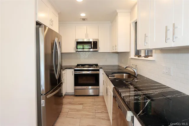 a kitchen with granite countertop a sink and a stove top oven with wooden floor