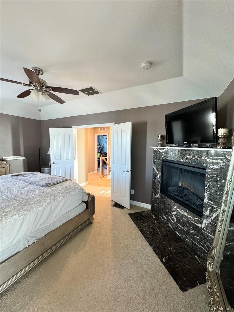 5546 Drake Street Frederick, CO 80504 - Photo 15 of 25 a spacious bedroom with a large bed a flat tv screen and a fireplace