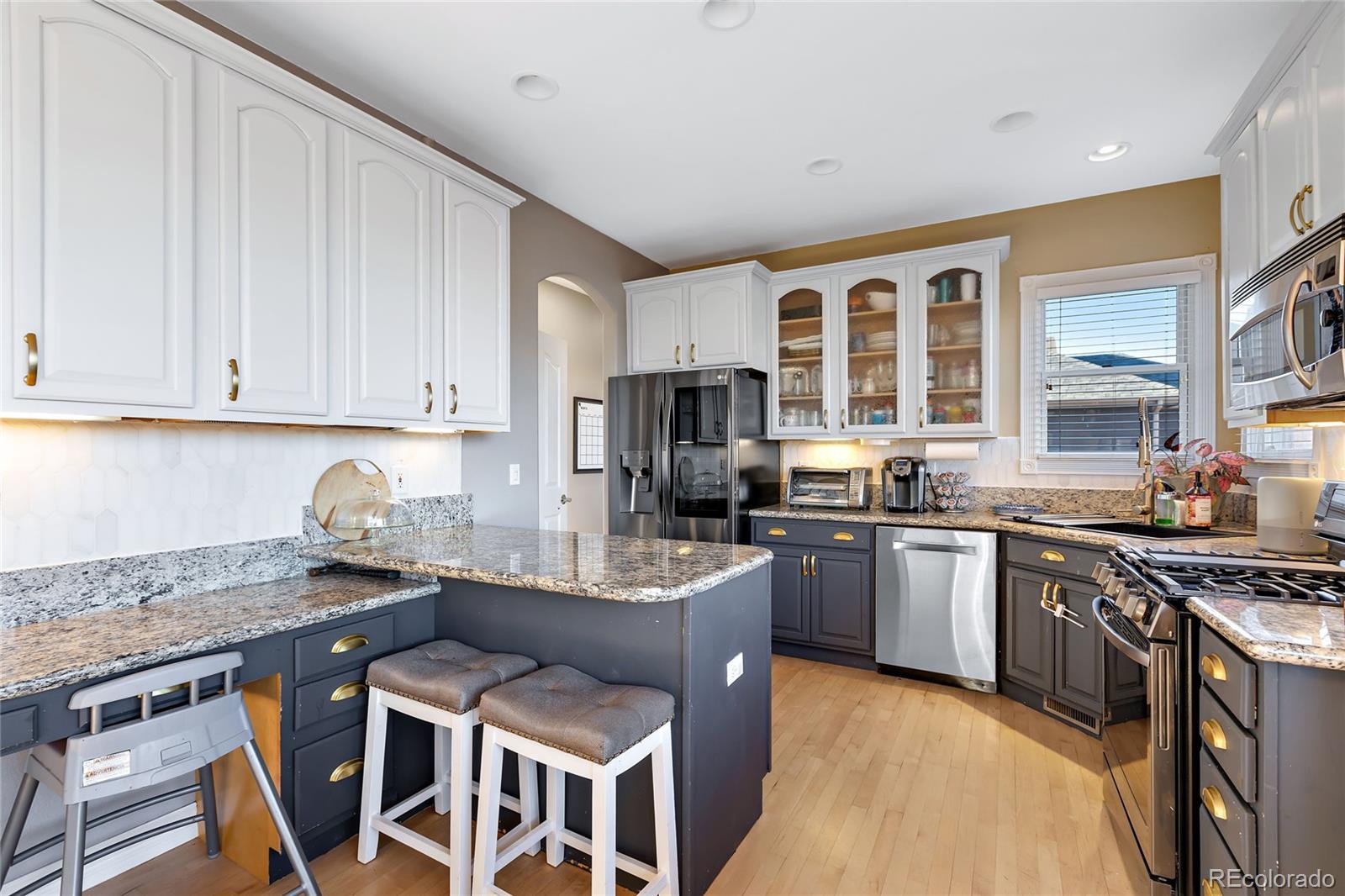 5546 Drake Street Frederick, CO 80504 - Photo 6 of 25 a kitchen with stainless steel appliances granite countertop a stove top oven a sink dishwasher a dining table and chairs with wooden floor