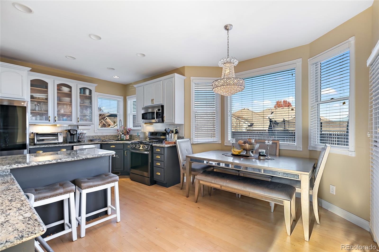5546 Drake Street Frederick, CO 80504 - Photo 7 of 25 a kitchen with a stove a sink dishwasher a dining table and chairs with wooden floor