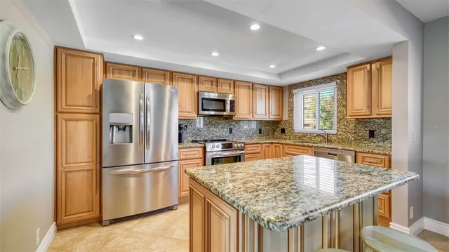 a kitchen with stainless steel appliances granite countertop a refrigerator a stove and a sink